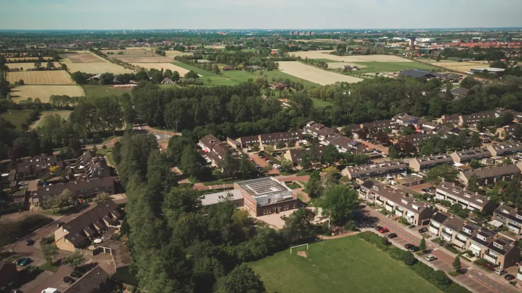 Vue aérienne d'un quartier résidentiel européen avec des écoles et des espaces verts.