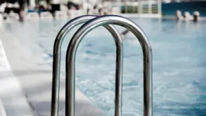 Gros plan sur l'échelle métallique d'une piscine publique en extérieur.
