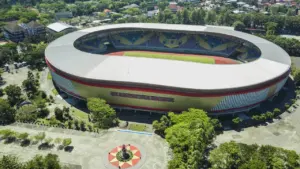 Vue aérienne d'un grand stade moderne entouré d'arbres, symbolisant le sport local.