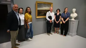 Un groupe de six personnes pose devant un tableau ancien dans un musée élégant.