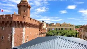 Vue panoramique sur l'architecture historique et les toits de Perpignan sous un ciel ensoleillé