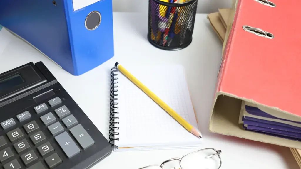 Fournitures scolaires, calculatrice et dossiers organisés sur un bureau pour la rentrée.