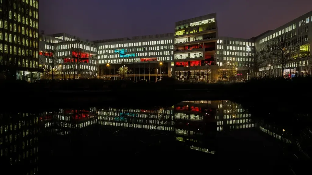 Vue nocturne des bâtiments administratifs de Saint-Denis avec des lumières allumées.
