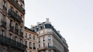 Architecture traditionnelle en pierre et immeubles haussmanniens sous un ciel clair à Paris.