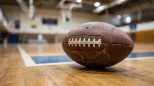 Un ballon de football américain usé posé sur le parquet d'un gymnase en salle.