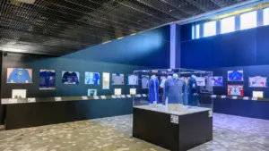 Exposition de maillots de football historiques sous vitrines dans un musée moderne aux murs bleus.