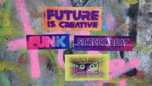 Autocollants urbains colorés sur un mur tagué évoquant la fête et la musique.