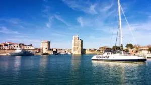 Bateau bleu et blanc au port de La Rochelle sous un ciel ensoleillé.