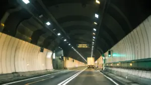 Vue intérieure d'un tunnel routier éclairé par des néons durant la nuit.