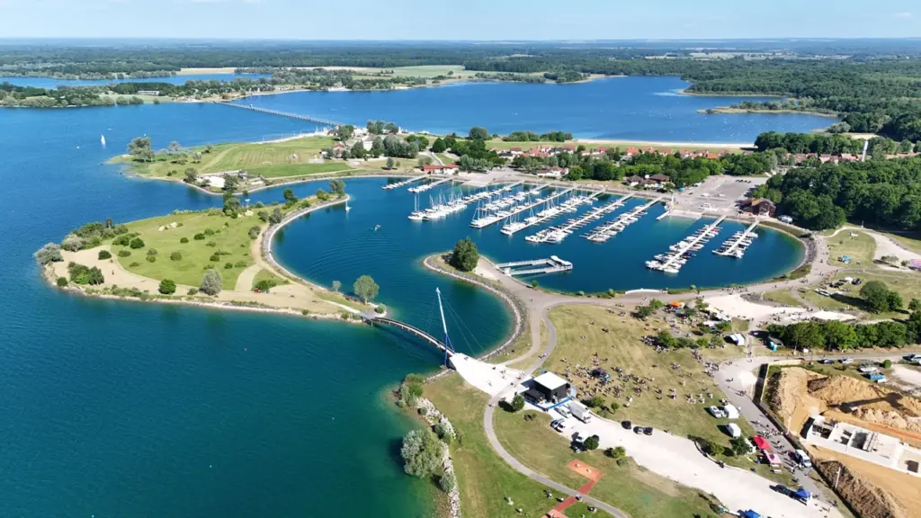 Vue aérienne d'un port de plaisance avec de nombreux bateaux sur un lac entouré d'arbres.