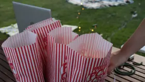 Sachets de popcorn rayés rouges et blancs sur une table pour une séance cinéma.