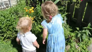 Deux jeunes enfants explorant un jardin luxuriant lors d'une journée ensoleillée.