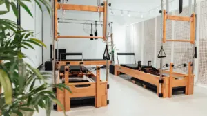 Salle de sport lumineuse équipée de machines de Pilates en bois et métal.