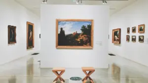 Vue intérieure d'une galerie d'art contemporain avec des peintures encadrées sur les murs blancs.