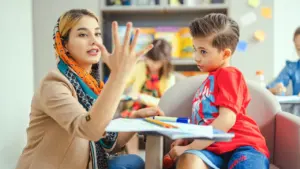 Une enseignante montre des chiffres avec ses doigts à un jeune enfant attentif.