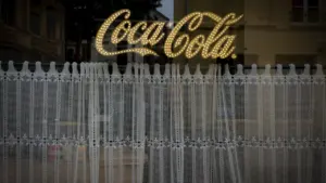Enseigne néon Coca-Cola derrière des rideaux en dentelle dans une fenêtre d'estaminet à Lille.