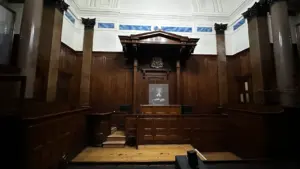 Vue intérieure d'une salle d'audience judiciaire vide avec boiseries et colonnes classiques.