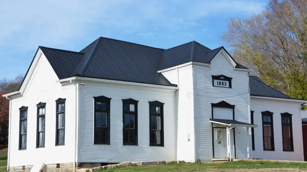 Bâtiment scolaire historique rénové avec une façade blanche et un toit moderne noir.