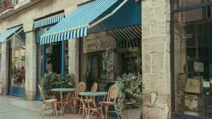 Terrasse d'un café avec auvents à rayures bleues dans une rue traditionnelle française.