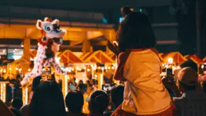 Enfants admirant une performance de danse du lion lors d'un événement festif nocturne.
