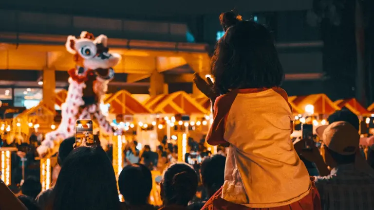 Enfants admirant une performance de danse du lion lors d'un événement festif nocturne.
