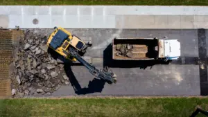 Vue aérienne d'une pelleteuse jaune retirant le bitume d'une route en travaux.