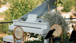 Un piano à queue blanc installé en extérieur avec des compositions florales élégantes.