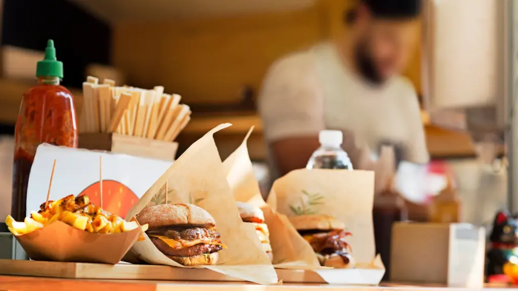 Des burgers et des frites servis dans des emballages en papier dans un food truck.
