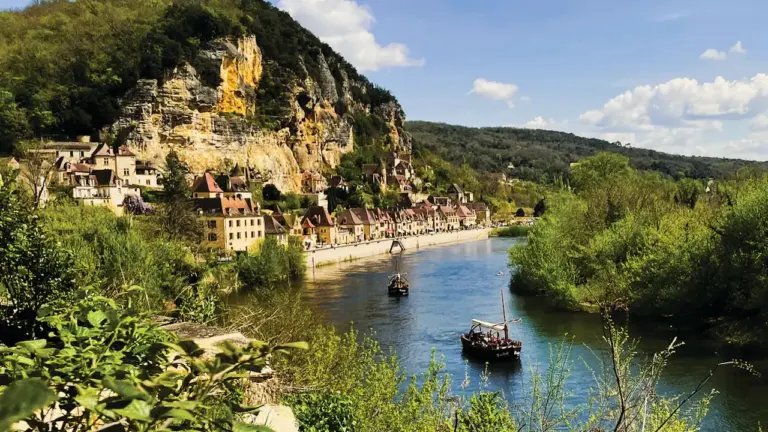Vue pittoresque d'une rivière en France avec des bateaux traditionnels et des villages.
