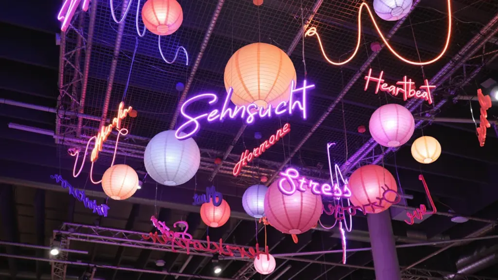 Installation artistique avec des néons et lanternes suspendues évoquant les émotions et pensées.